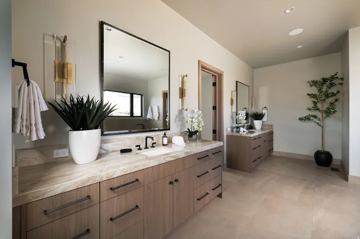 Dual vanity with wood-finish cabinetry, stone countertops, and matte black fixtures