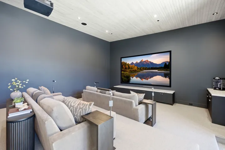 Media room featuring a large projection screen, built-in cabinetry with light-toned countertops, and a white wood-paneled ceiling with recessed lighting