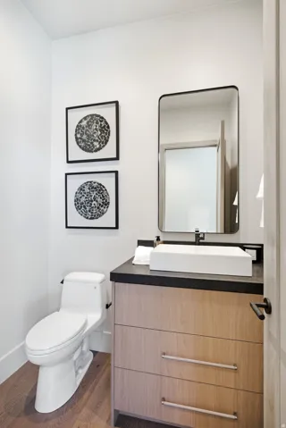 Modern vanity with wood-finish drawers, dark countertop, and a rectangular vessel sink