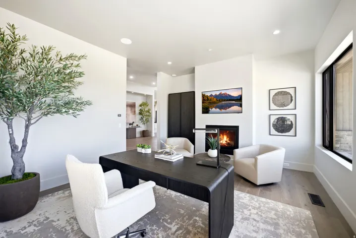 Built-in fireplace with hearth, recessed lighting, wood-finish flooring, and a large window