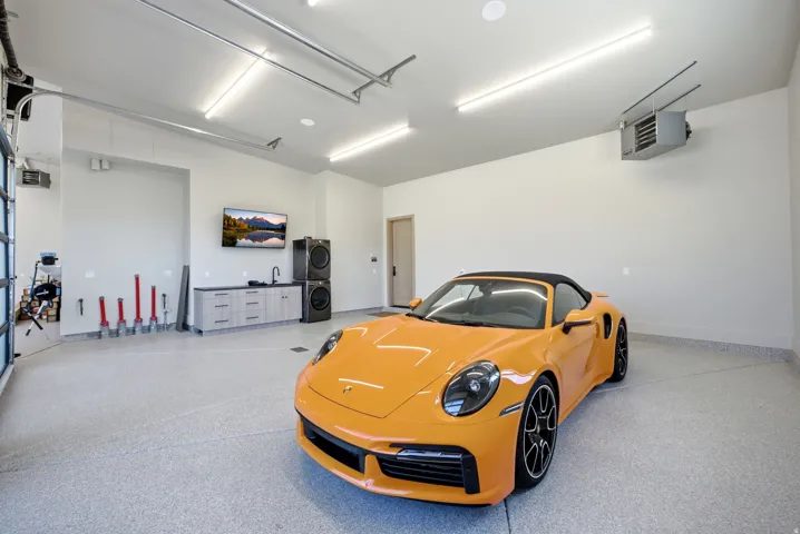 Spacious garage with an epoxy finished floor, built-in cabinetry, utility sink, and wall-mounted heating unit