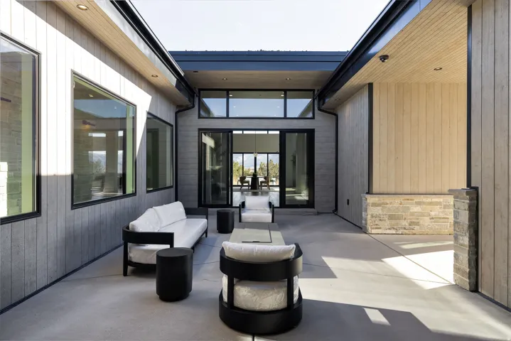 Expansive outdoor patio featuring a concrete surface, modern wood-paneled walls, and large black-framed windows