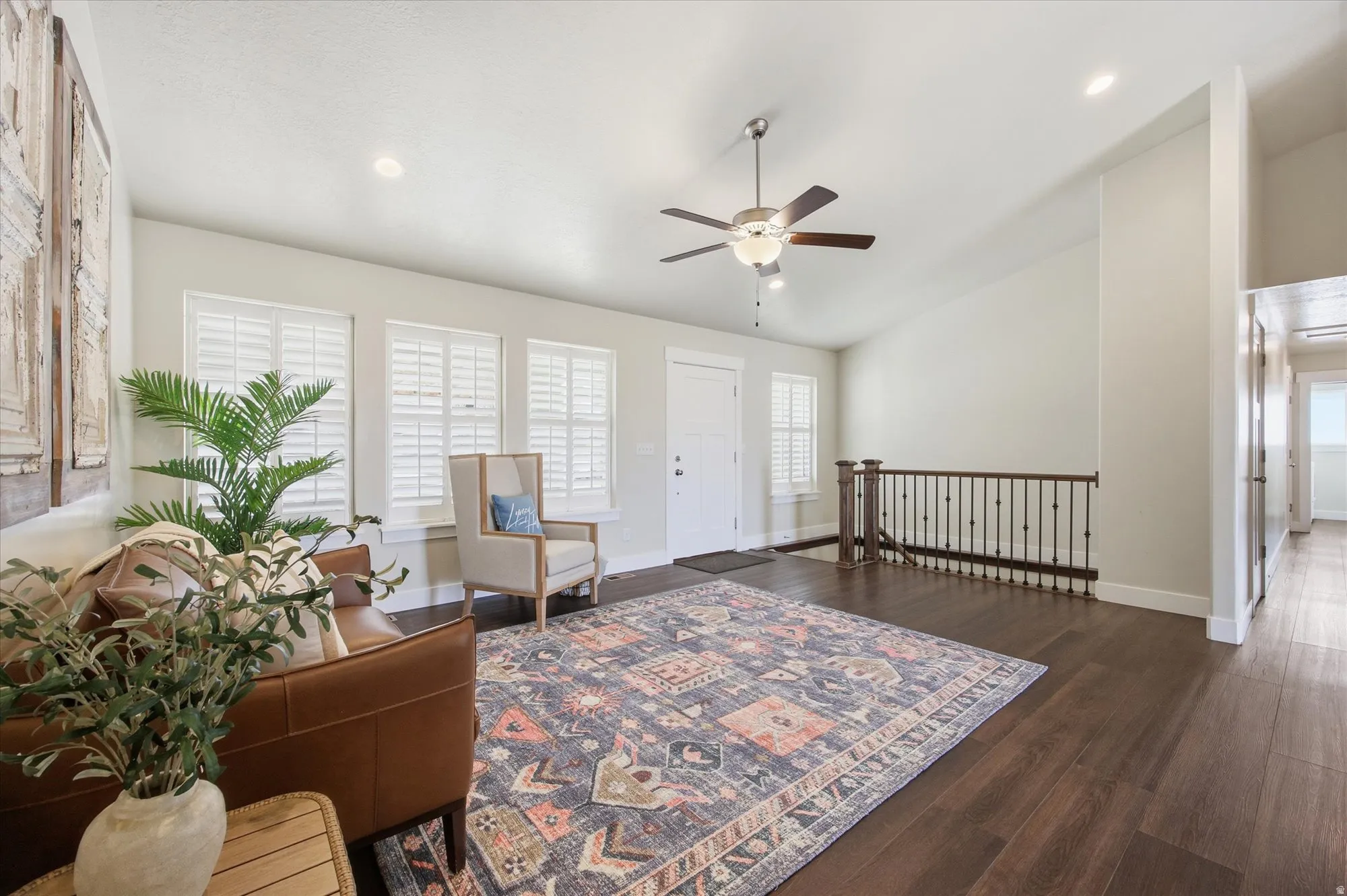 Sitting room with a ceiling fan, dark wood-style floors, vaulted ceiling, an upstairs landing, and recessed lighting