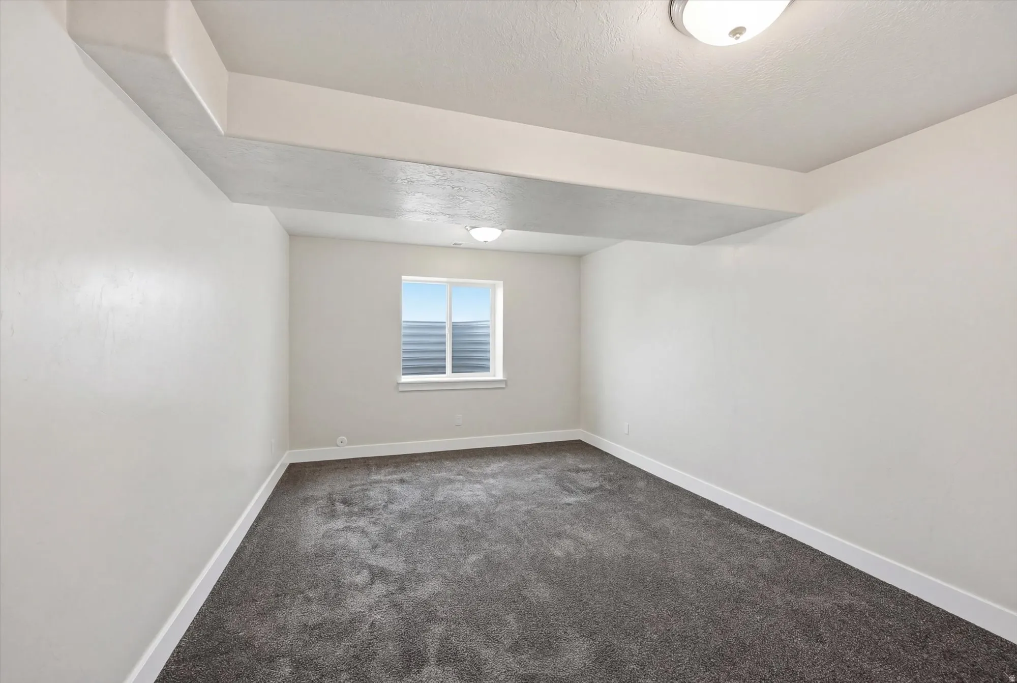 Spare room with dark colored carpet and a textured ceiling