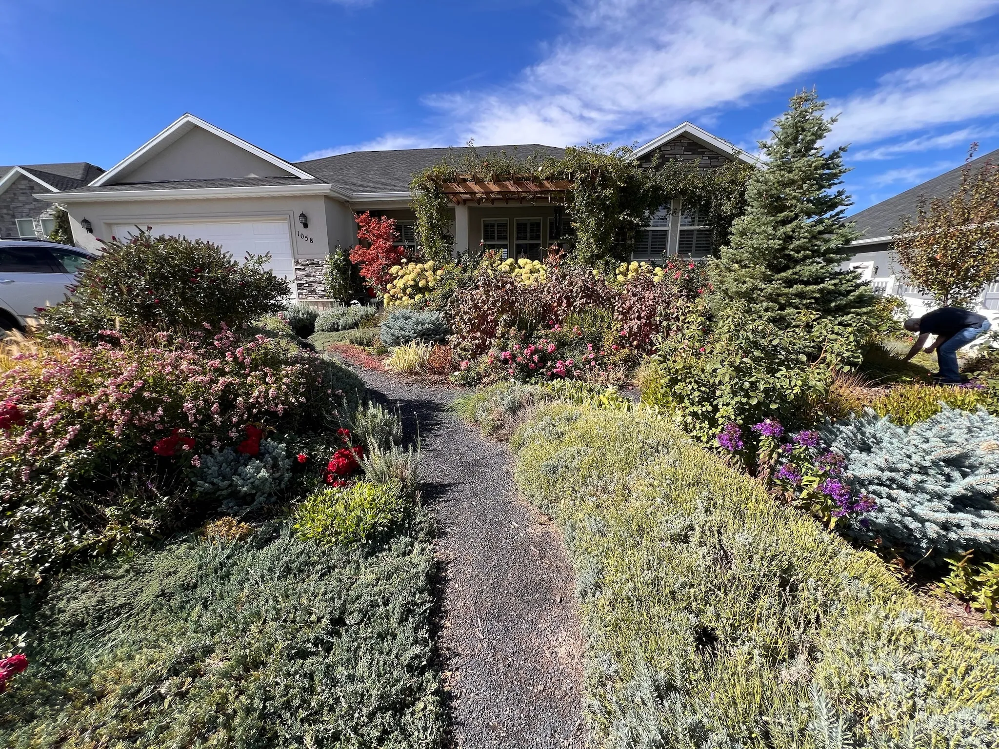 SUMMER    View of front facade featuring a garage and stone siding