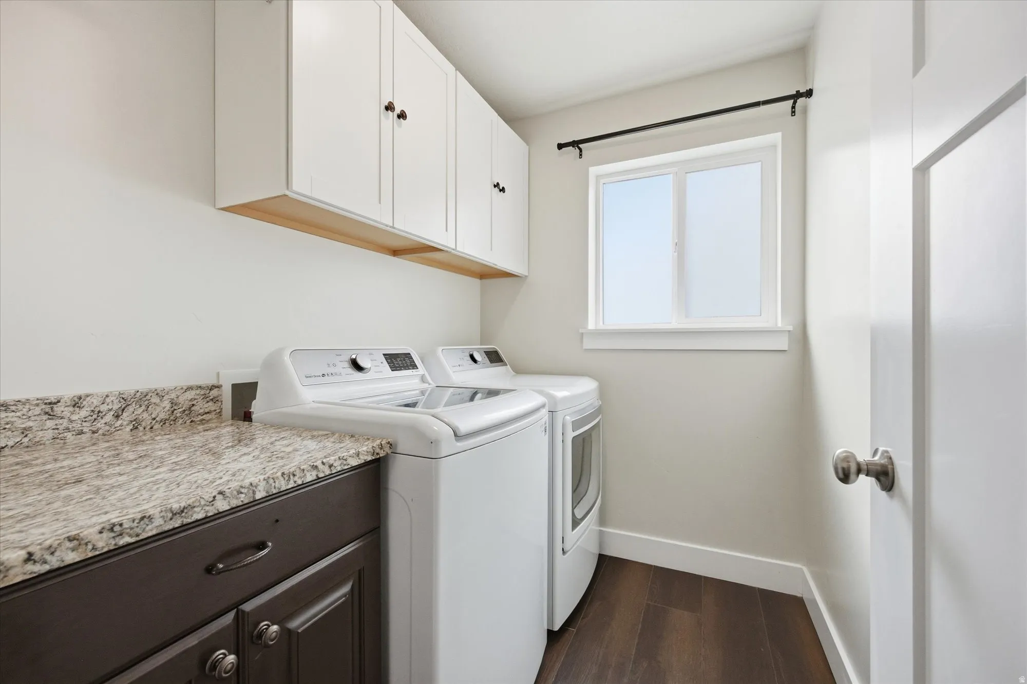 Laundry room featuring cabinet space, dark wood-type flooring, and washing machine and clothes dryer