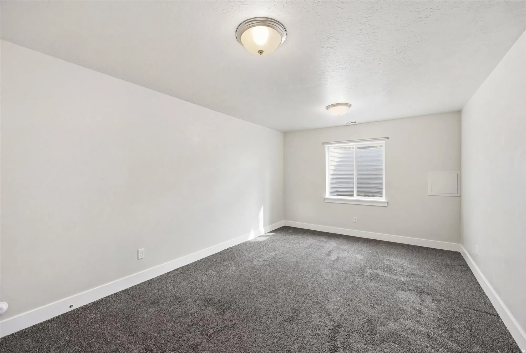 Empty room featuring dark colored carpet and a textured ceiling