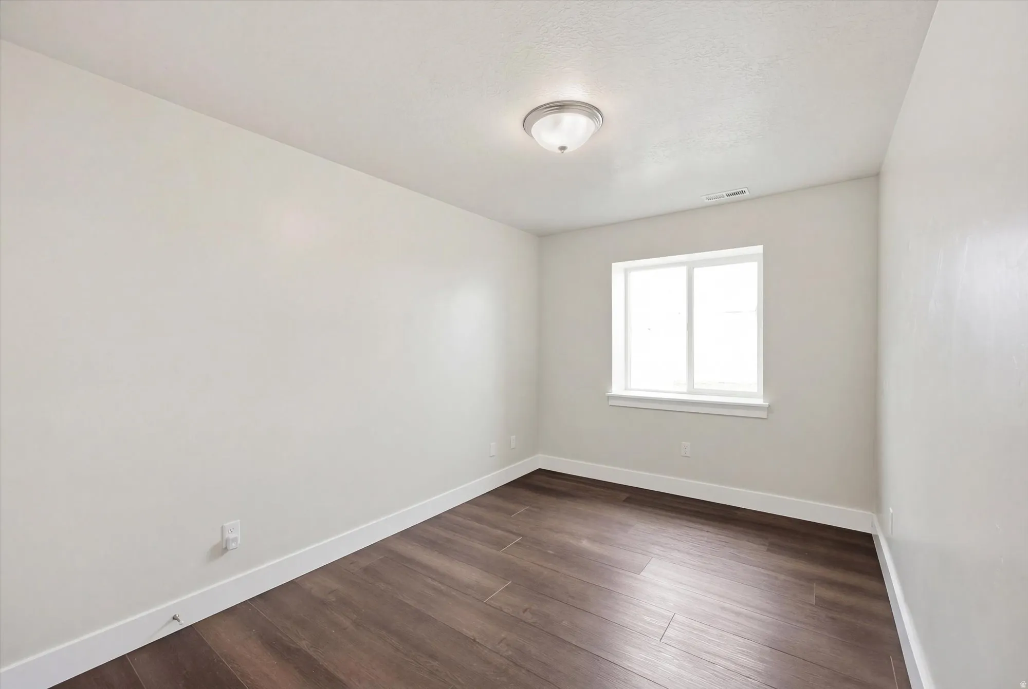 Empty room with baseboards and dark wood-style flooring