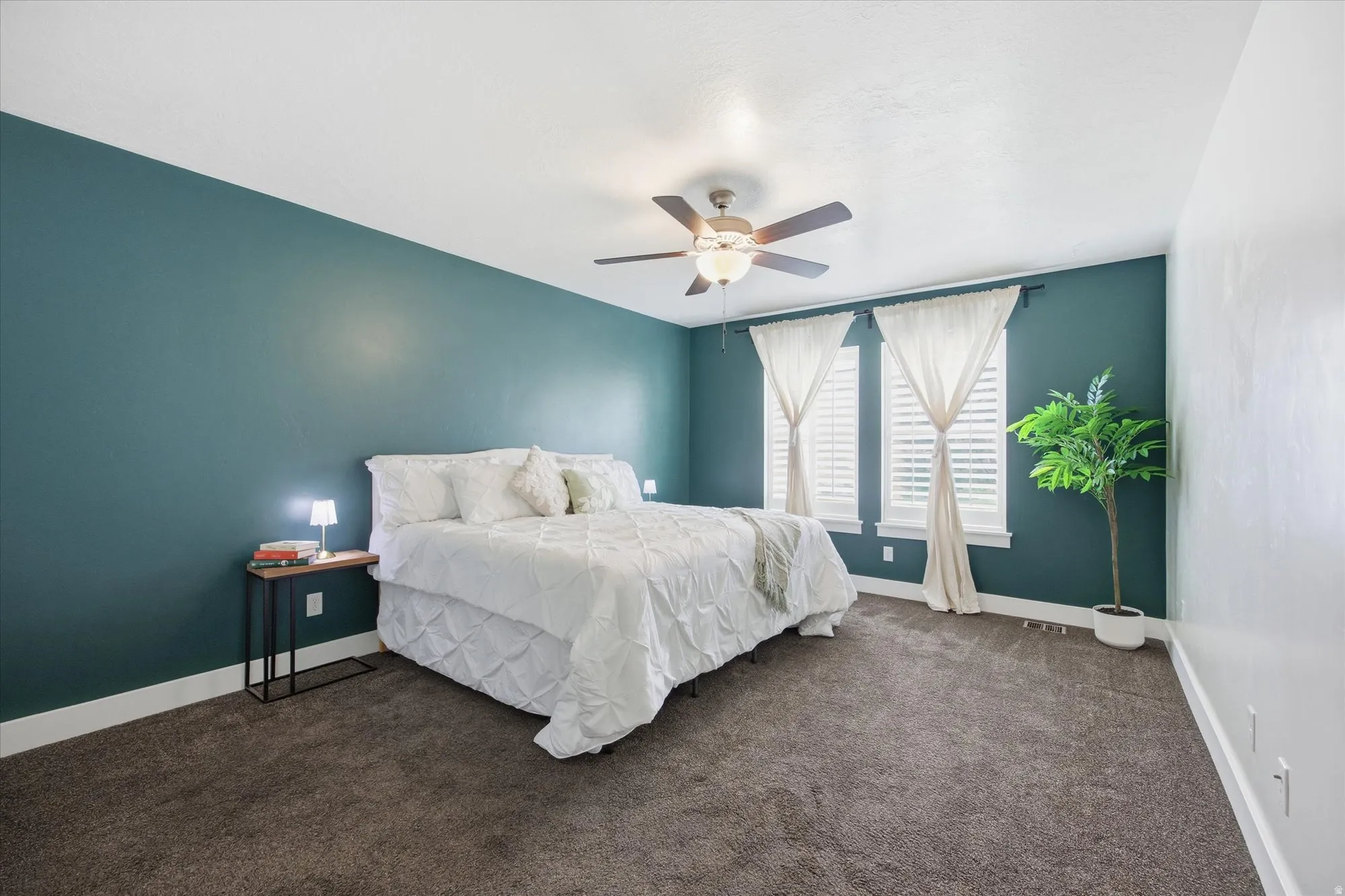 Bedroom with dark colored carpet and a ceiling fan