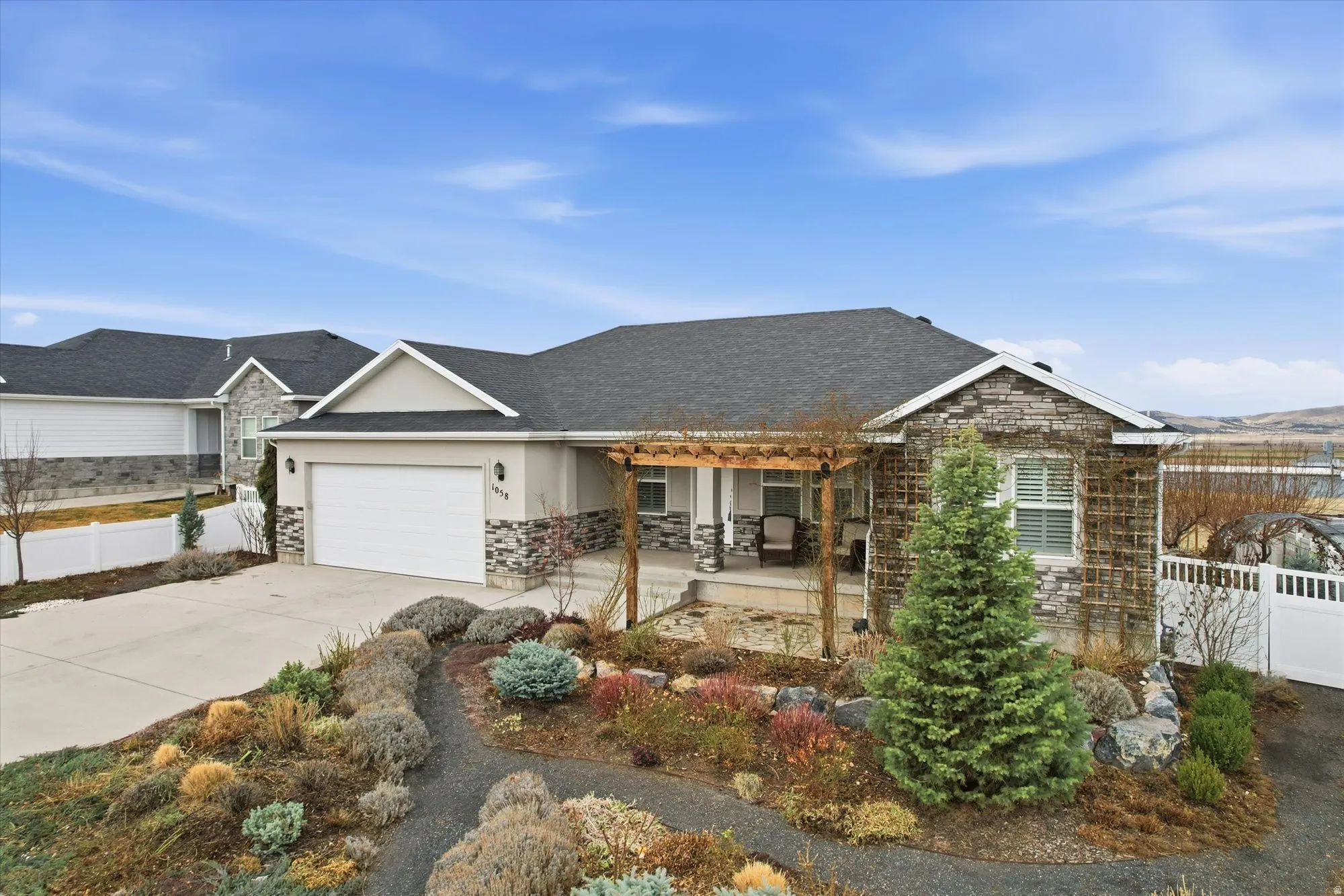 View of front of house with concrete driveway, an attached garage, stone siding, stucco siding, and covered porch