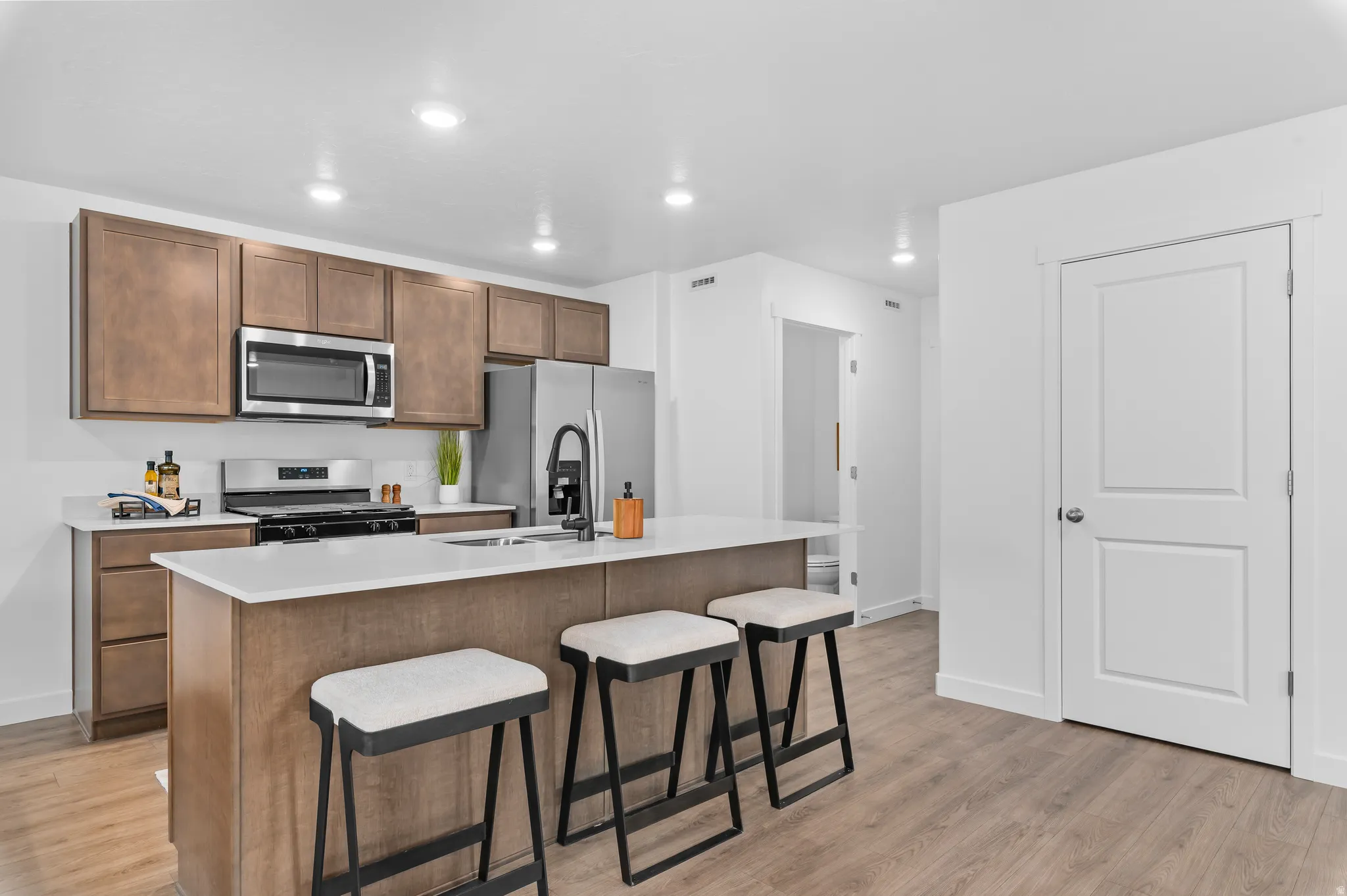 Kitchen featuring an island with sink, a breakfast bar, stainless steel appliances, light wood-type flooring, and recessed lighting