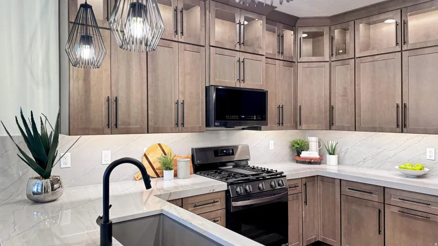 Kitchen featuring stainless steel appliances, glass fronted cabinets, light stone counters, and tasteful backsplash