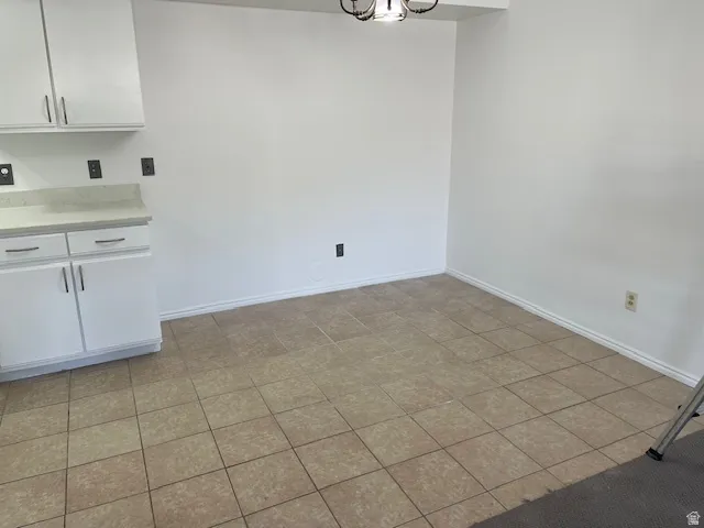 Unfurnished dining area featuring hanging lights and dark tile patterned floors