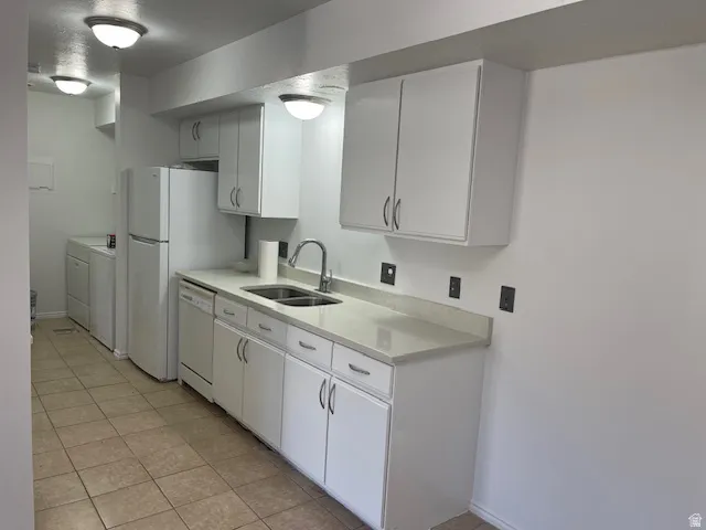 Kitchen with white cabinetry, dishwasher, light tile patterned floors, and independent washer and dryer