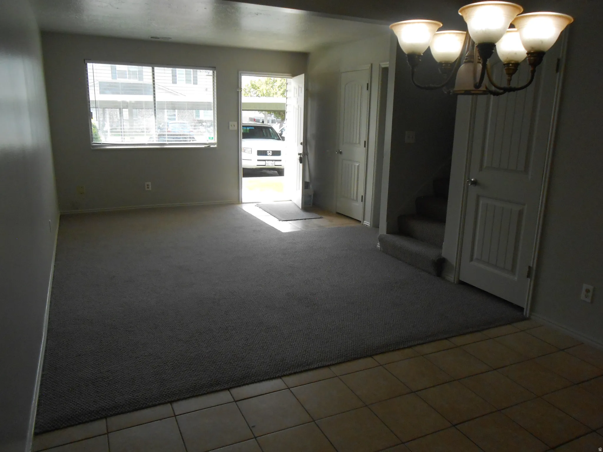 Empty room with suspended lighting and light colored carpet