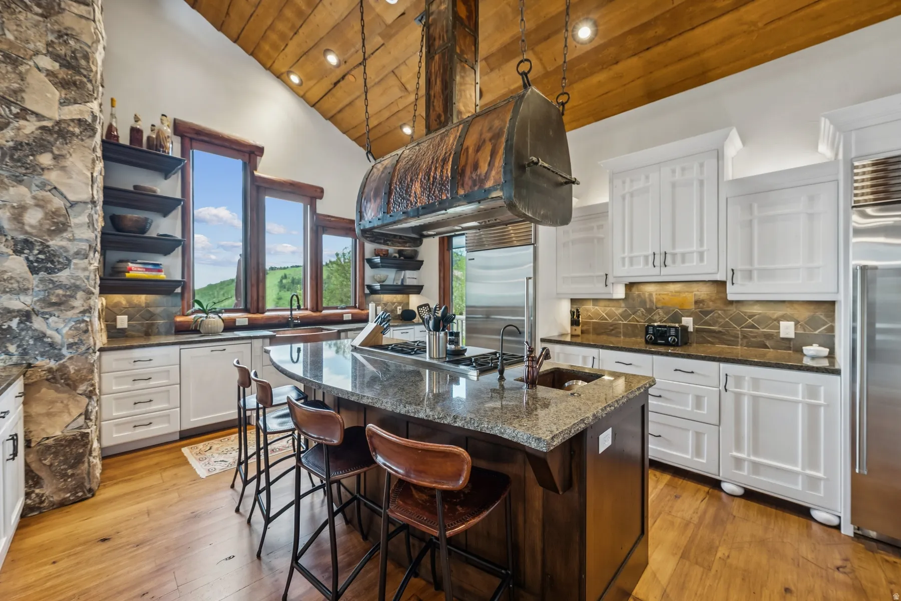 Two tone kitchen featuring a vaulted wooden ceiling, decorative backsplash, dark stone countertops, light wood-style floors, and a breakfast bar