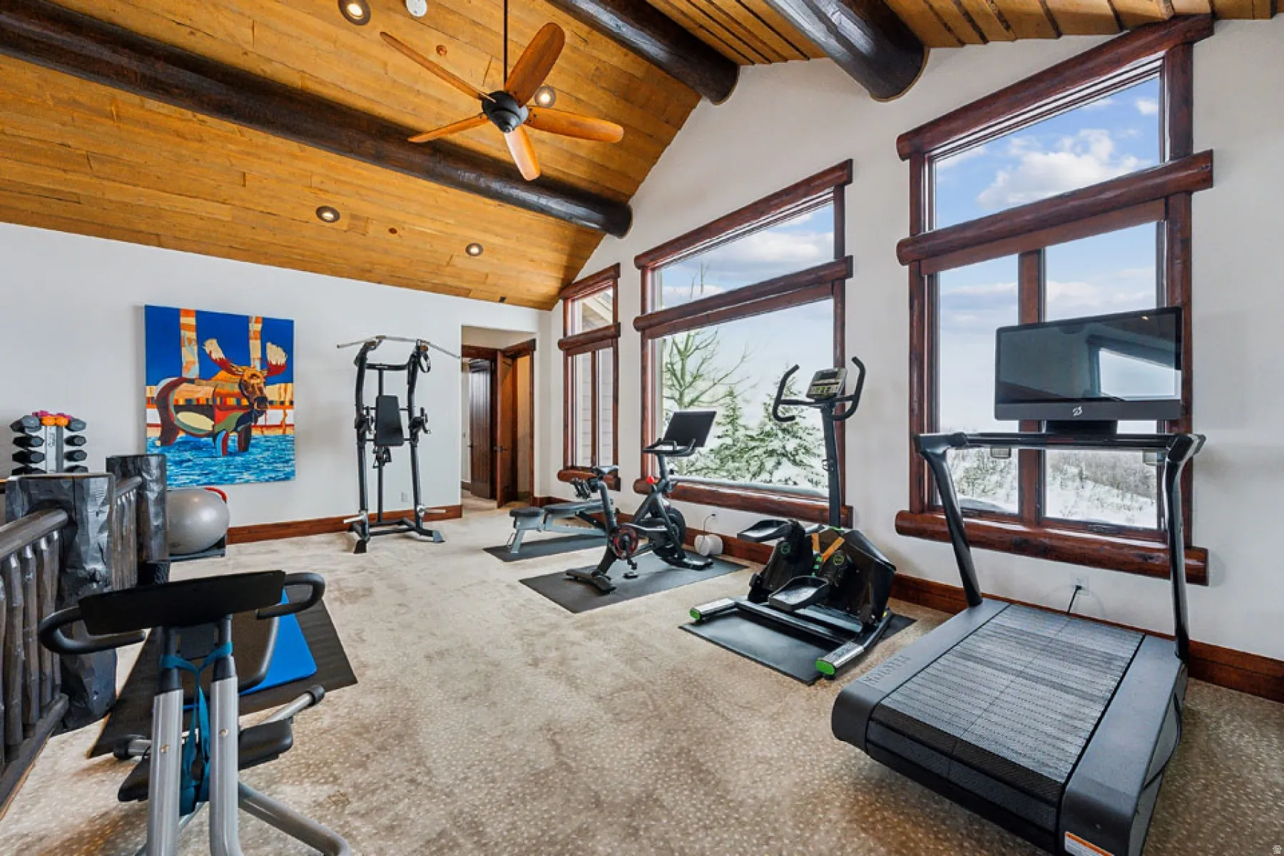 Exercise room featuring carpet floors, ceiling fan, and a high wooden beamed ceiling