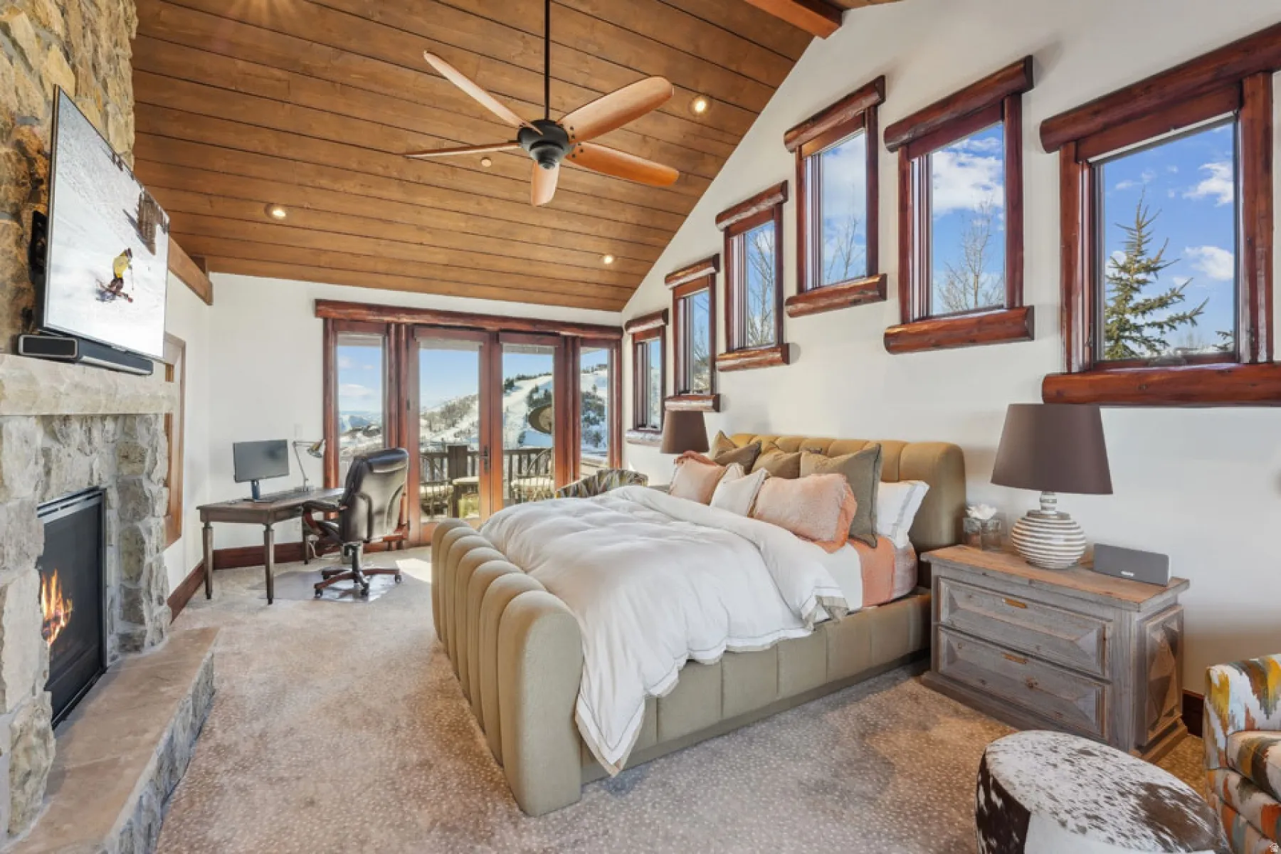 Bedroom with a stone fireplace, lofted ceiling with beams, access to exterior, recessed lighting, and a desk