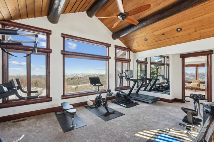 Gym featuring a high wooden beamed ceiling, a ceiling fan, and a mountain view