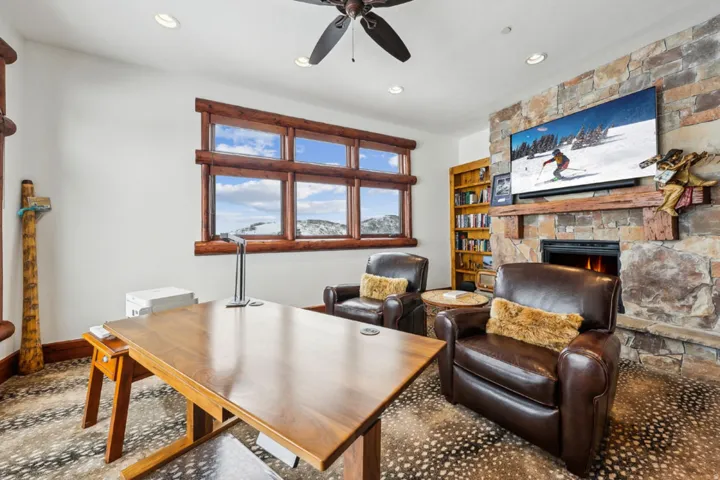 Office area featuring a stone fireplace, ceiling fan, and recessed lighting