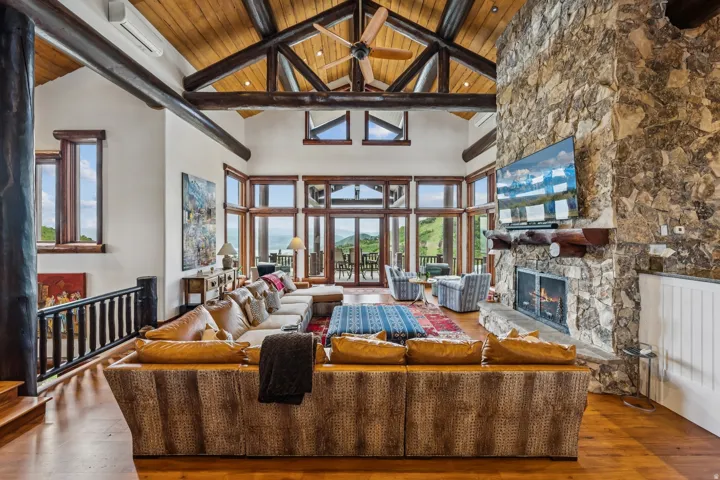Living room with a fireplace, a high wooden beamed ceiling, and wood-type flooring