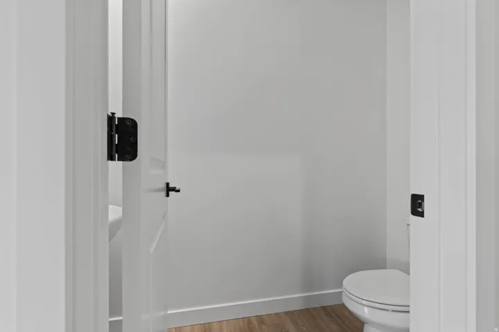 Powder room with wood-finish flooring, white walls, and a white toilet