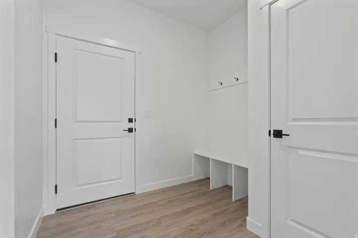 Entryway featuring light wood-finish flooring, white walls, and a built-in bench with storage cubbies and coat hooks