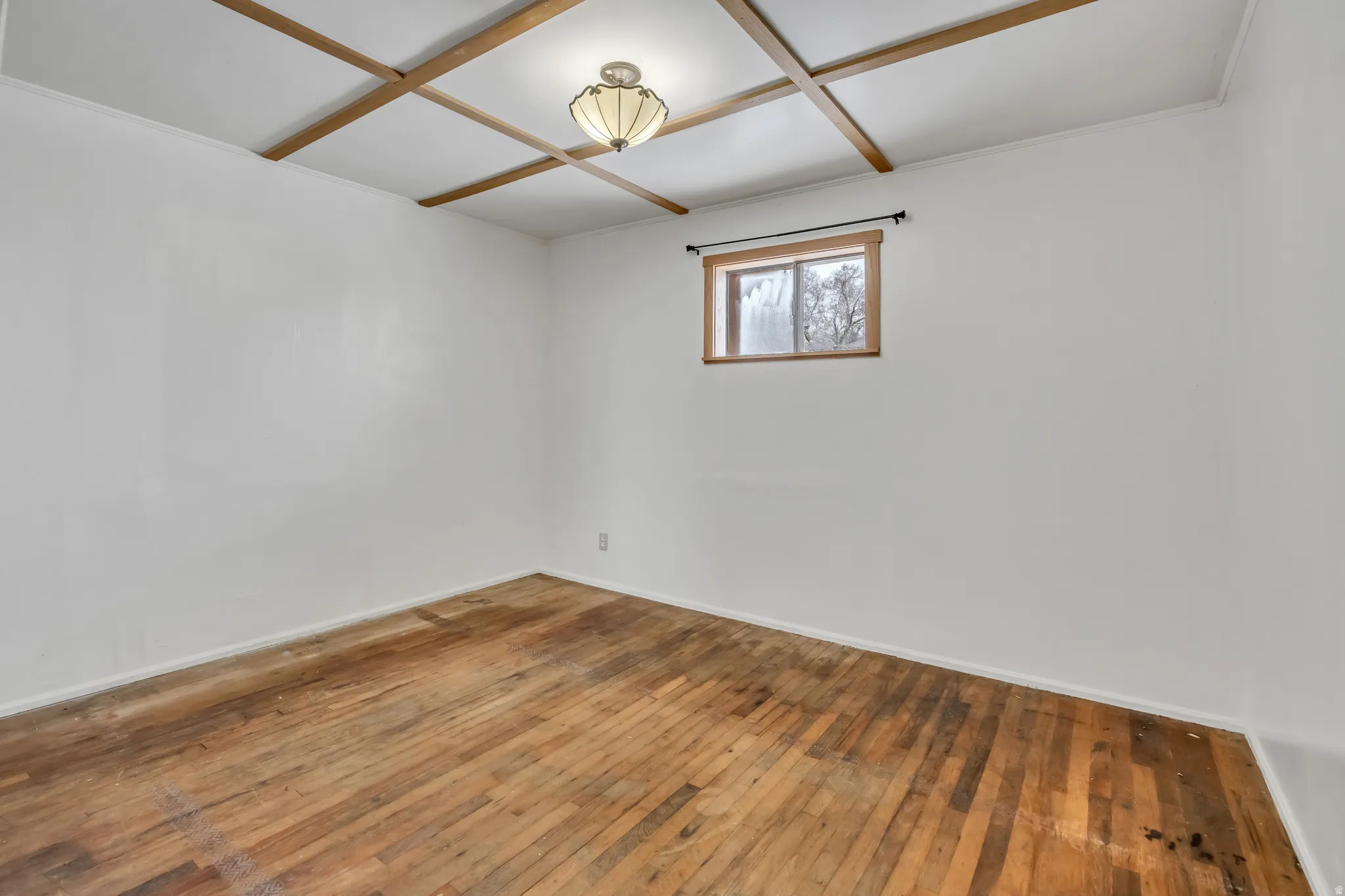 Empty room featuring wood-type flooring and coffered ceiling