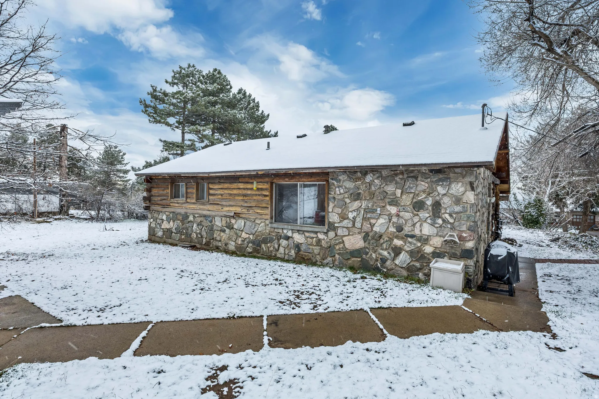 Snow covered house with stone siding and log siding