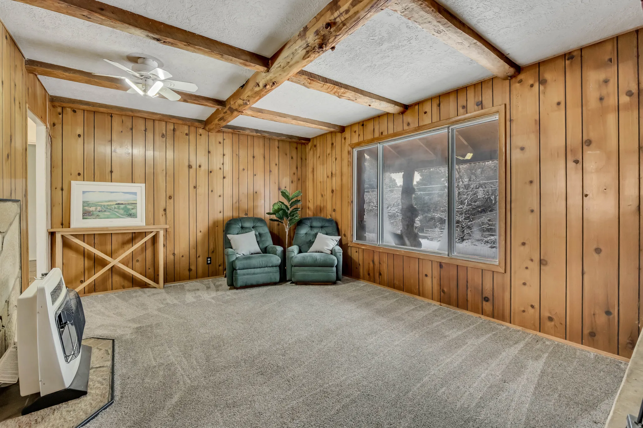 Living area featuring wood walls, beam ceiling, a textured ceiling, heating unit, and carpet