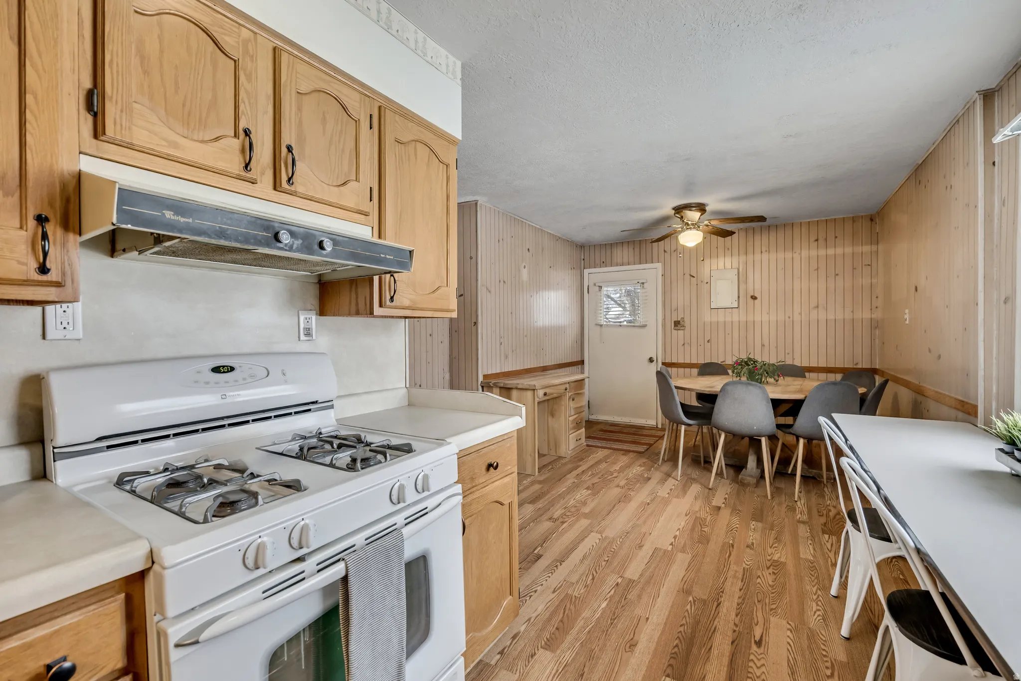 Kitchen featuring white gas range oven, light countertops, light wood-style flooring, light wood finish cabinetry, and ceiling fan