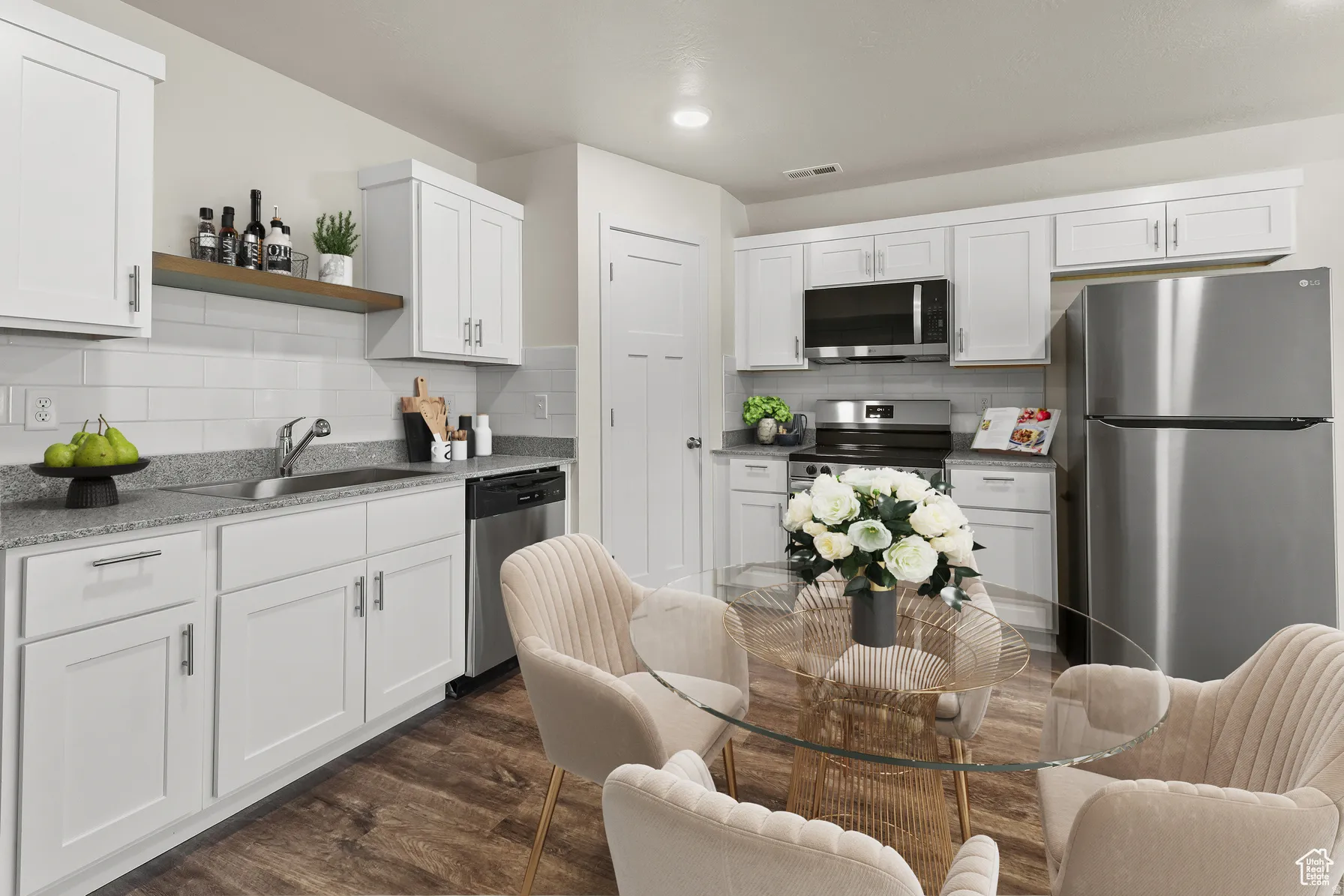 Kitchen with stainless steel appliances, white cabinets, dark wood-style floors, open shelves, and tasteful backsplash