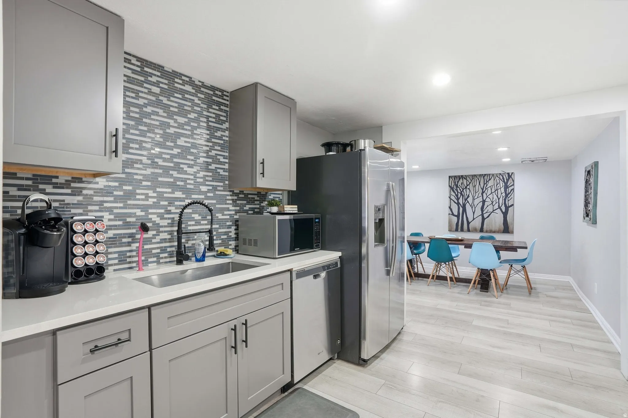 Kitchen featuring gray cabinets, stainless steel appliances, light wood finished floors, tasteful backsplash, and recessed lighting