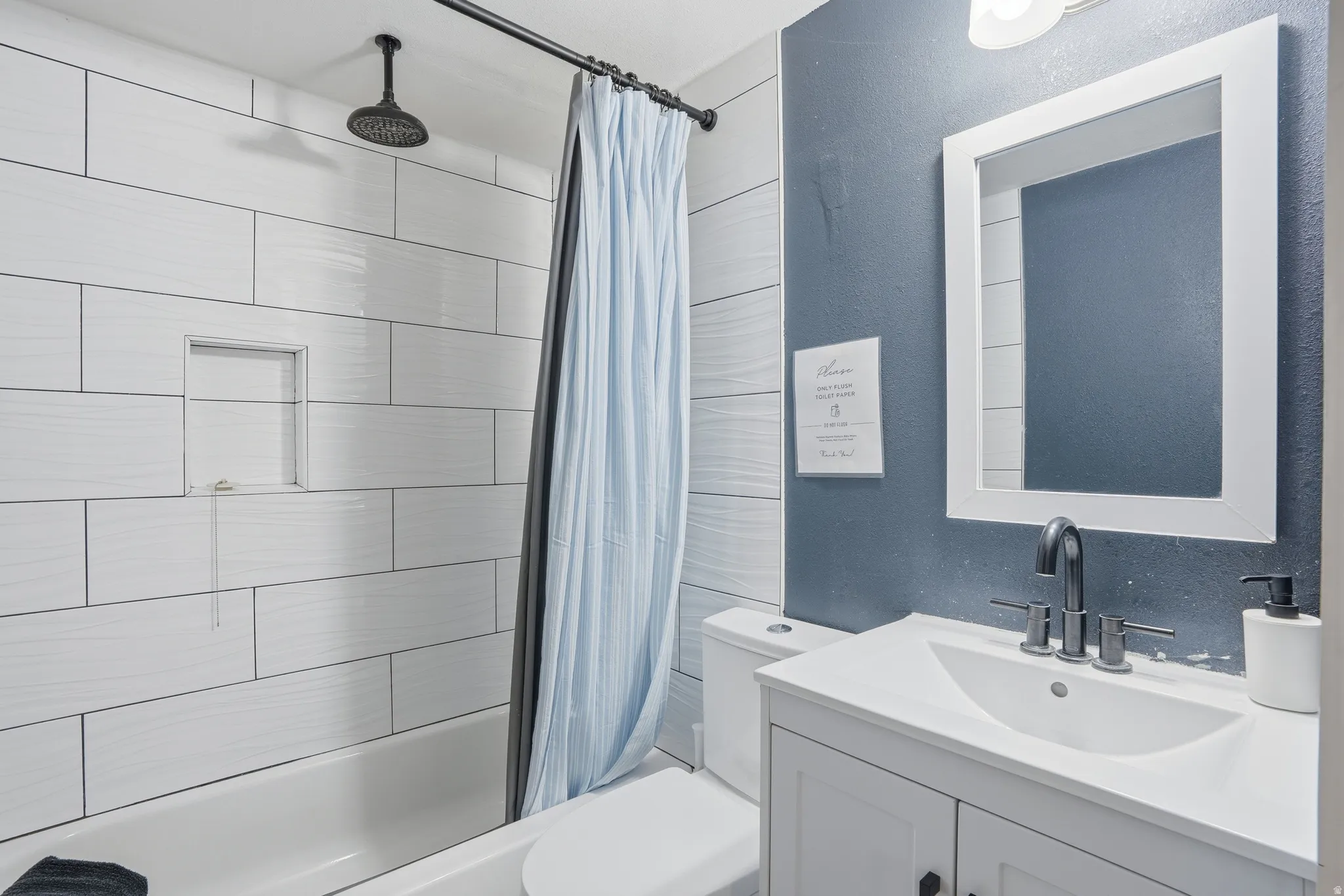 Full bathroom featuring a textured wall, vanity, and a combined bath / shower with rainfall shower