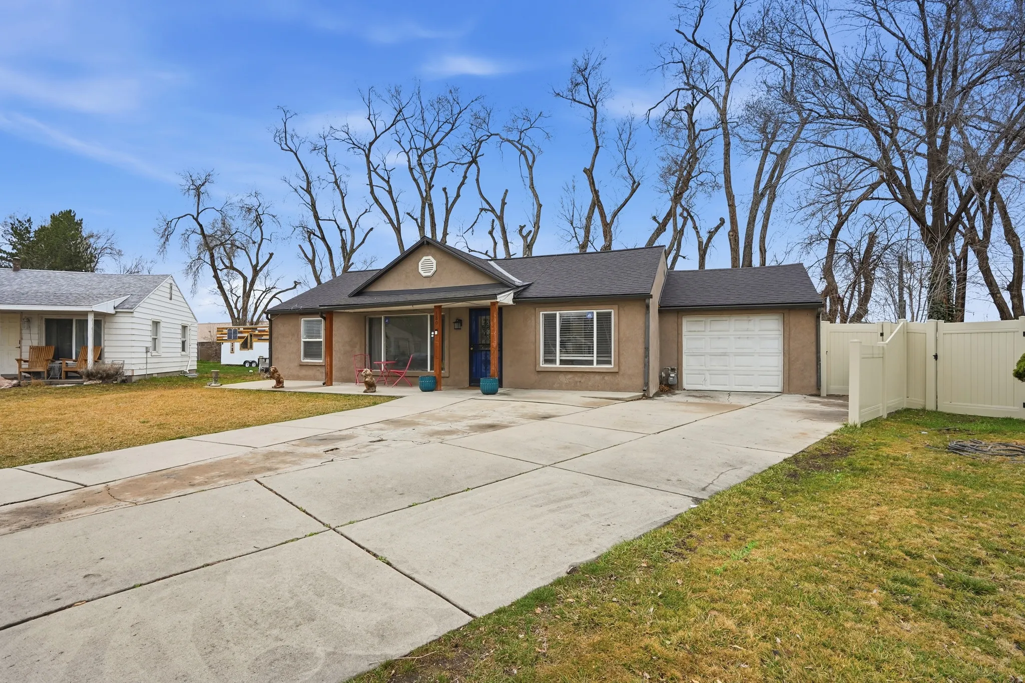 Ranch-style house featuring a gate, driveway, a garage, a porch, and stucco siding