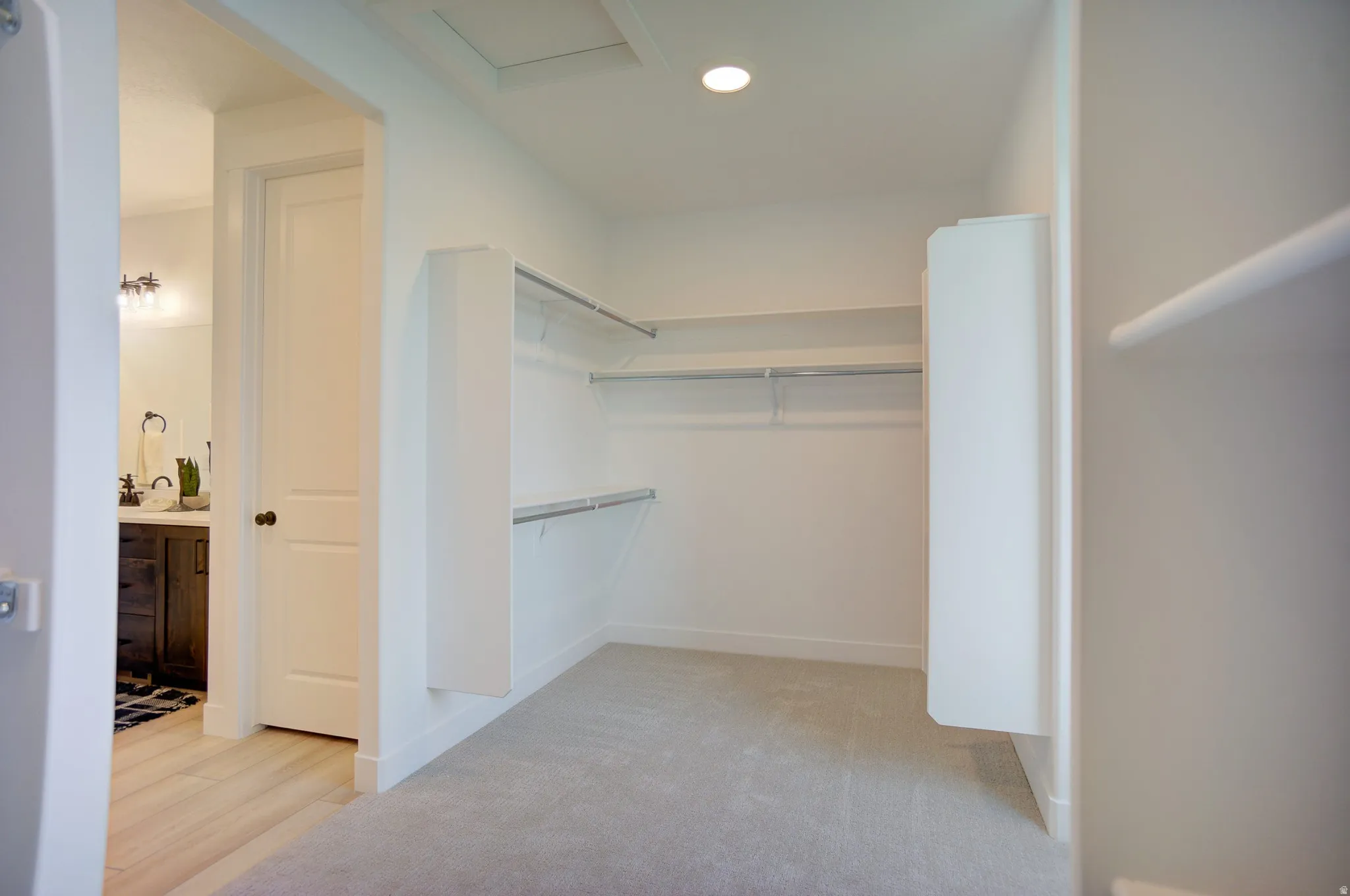 Walk in closet featuring attic access and light carpet