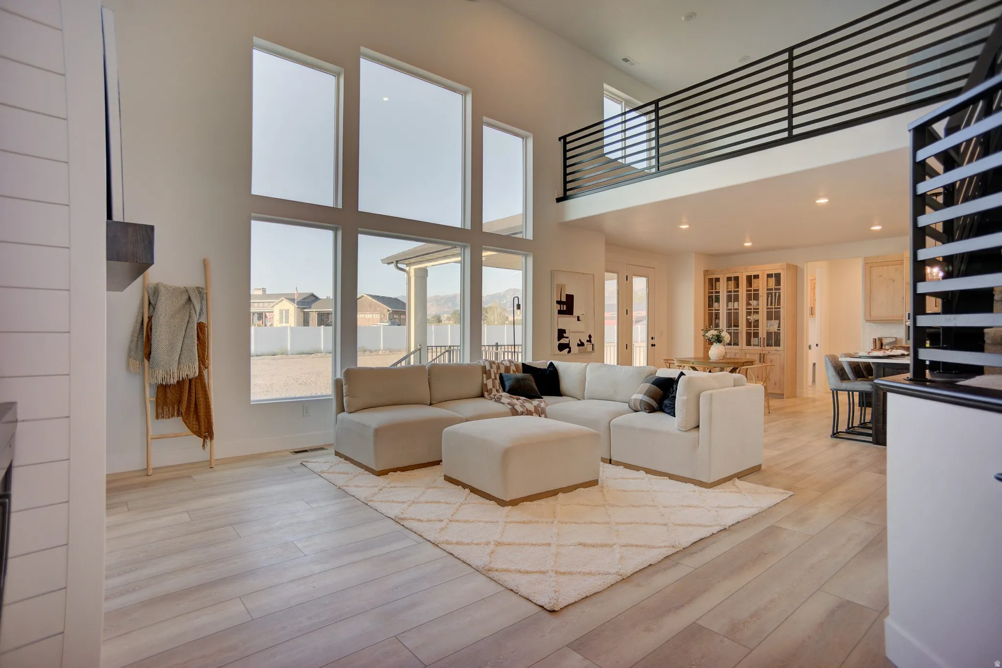 Living room with light wood-style floors, recessed lighting, a high ceiling, and a residential view