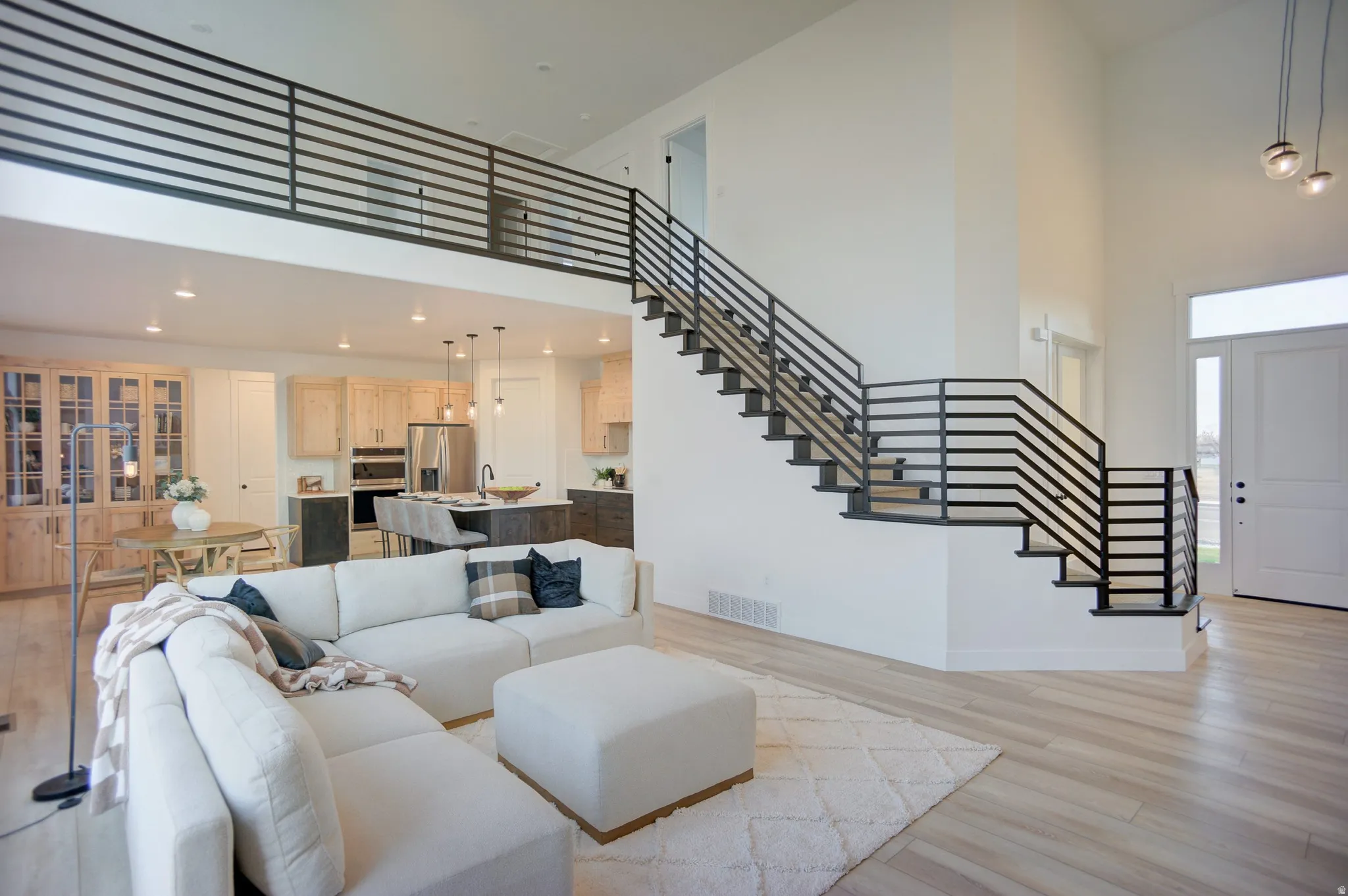 Living room featuring a high ceiling, light wood-style flooring, and recessed lighting