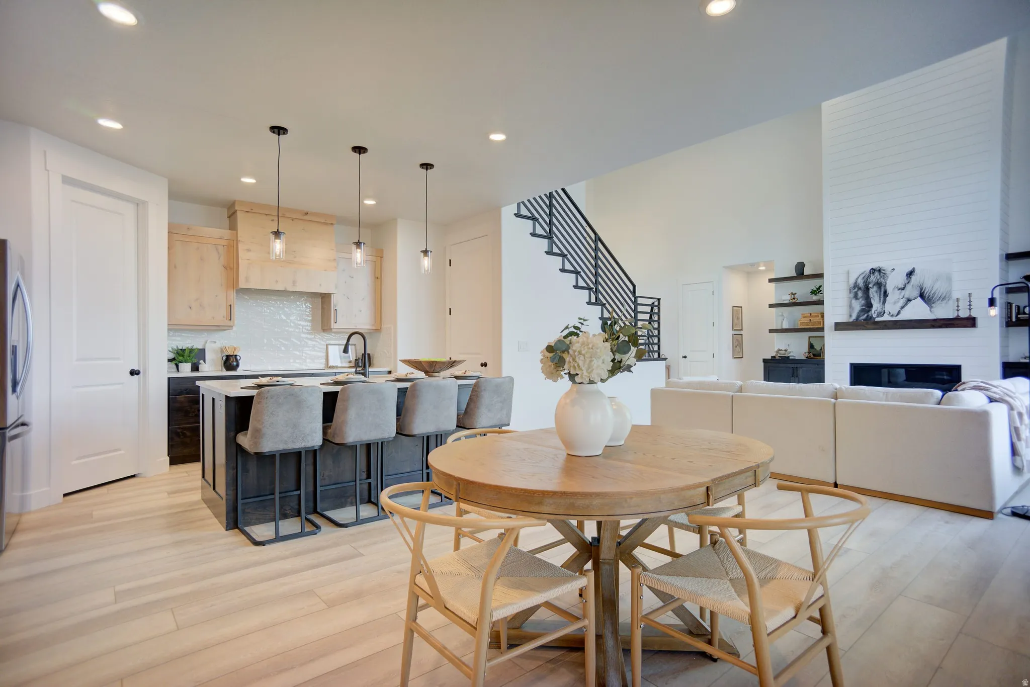Dining area featuring light wood-style floors, recessed lighting, and a large fireplace