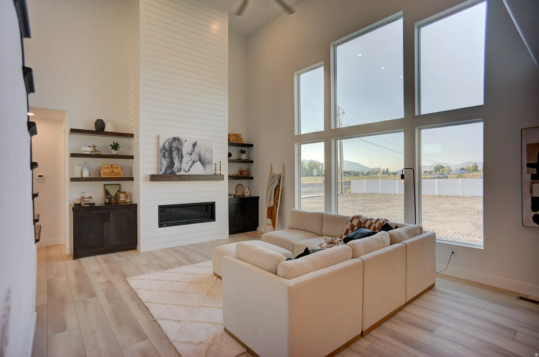Living area with a high ceiling, light wood-style floors, a large fireplace, and a water view