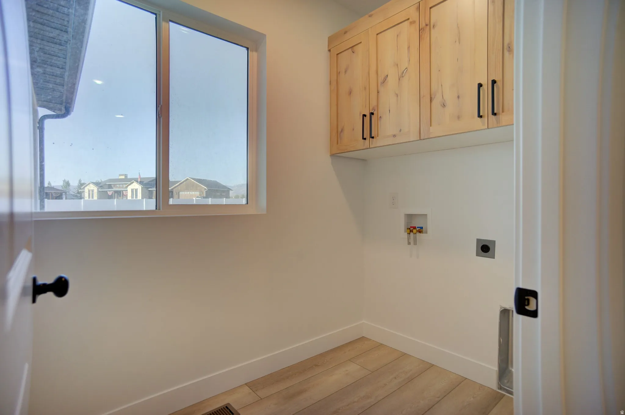 Laundry room with light wood-style floors, washer hookup, cabinet space, and hookup for an electric dryer