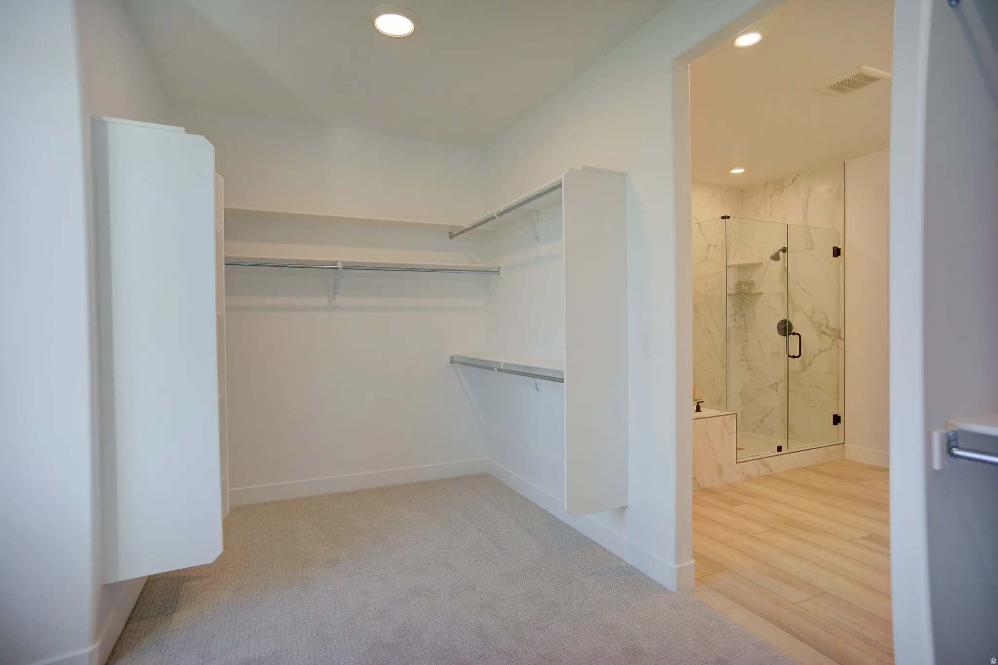Walk in closet with light colored carpet