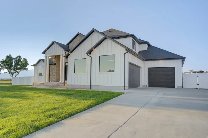 Modern farmhouse style home featuring board and batten siding, a gate, driveway, and a garage