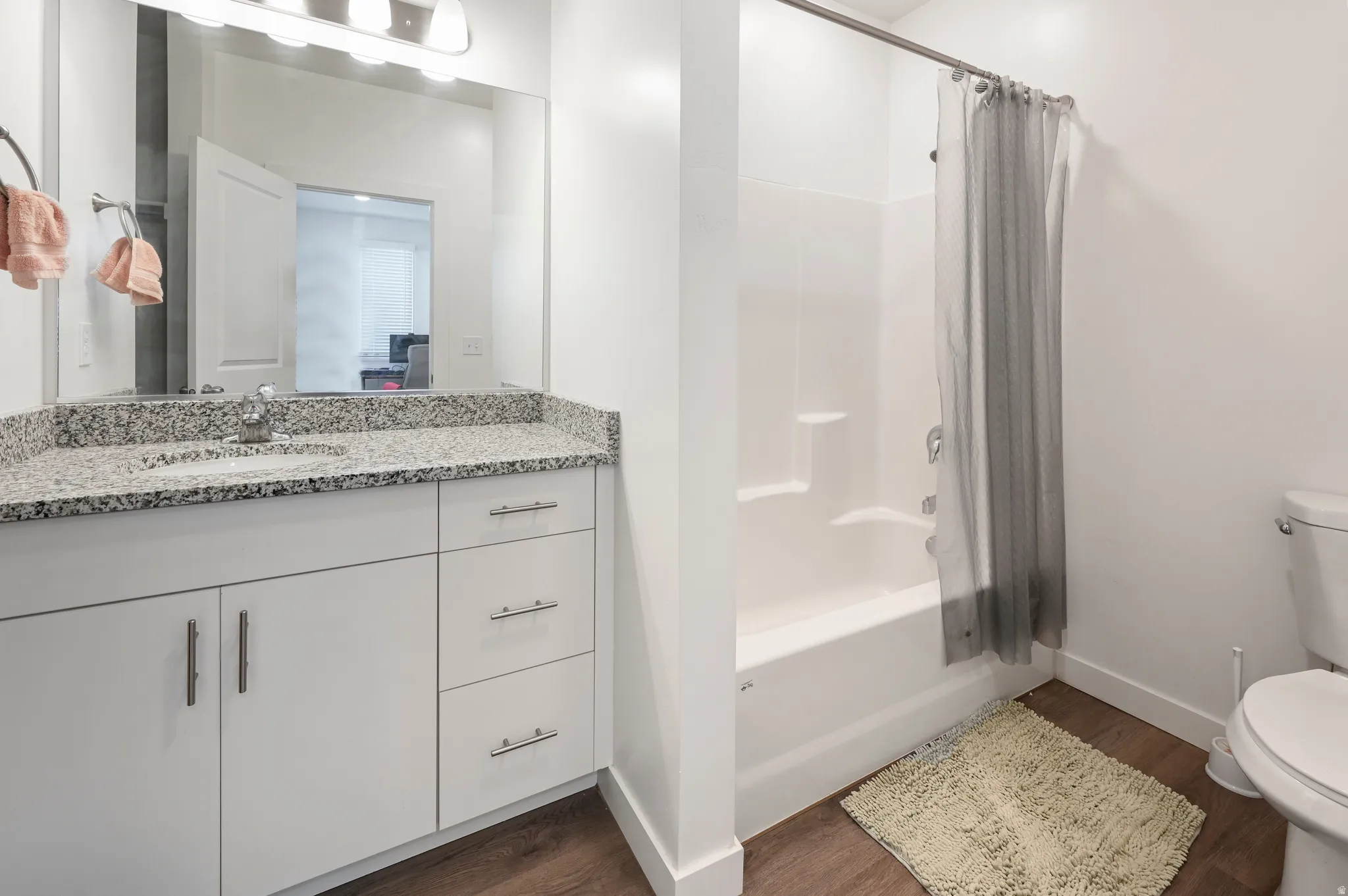 Full bathroom featuring shower / tub combo with curtain, vanity, and dark wood finished floors