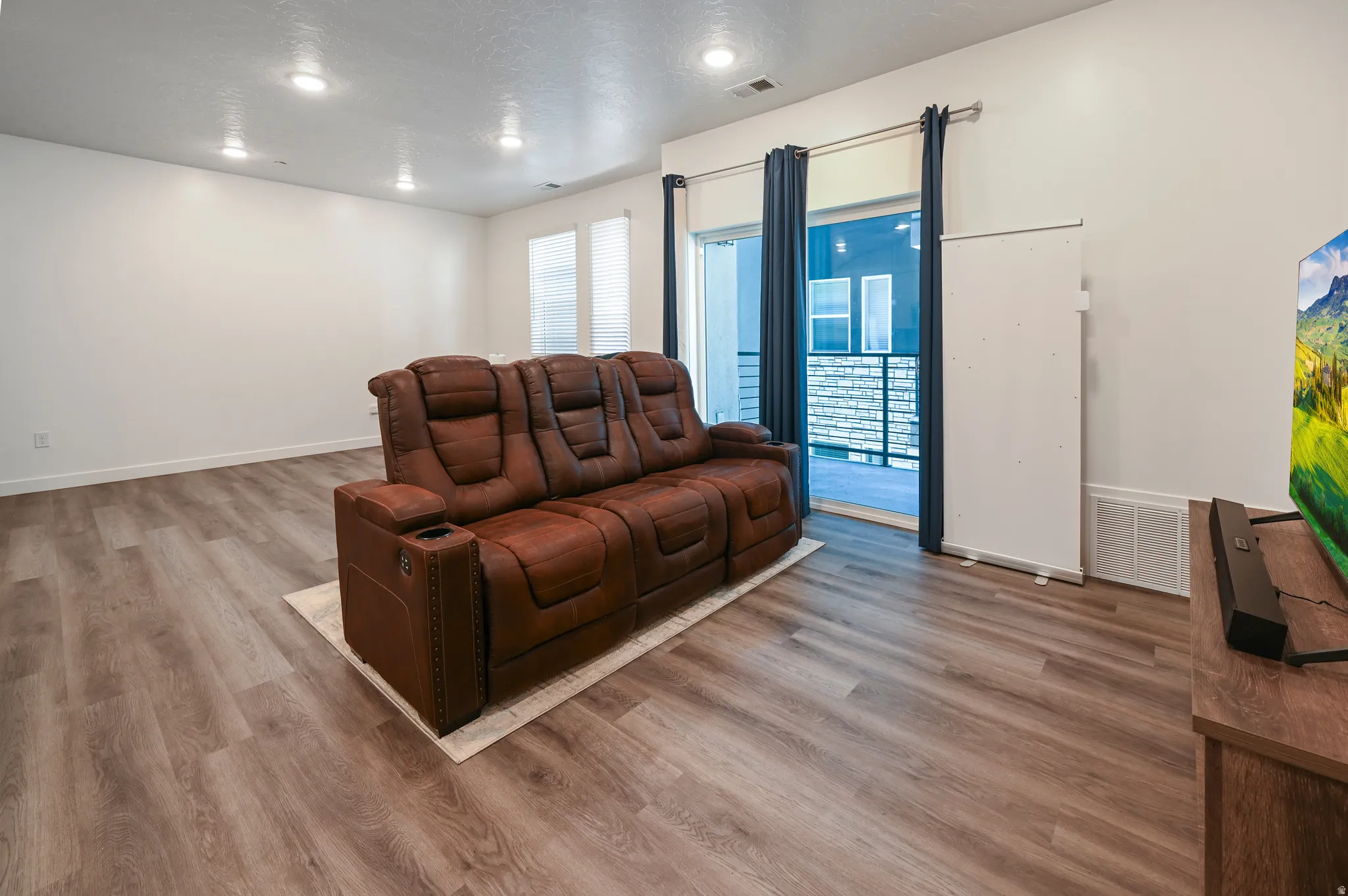 Home theater room featuring light wood finished floors, recessed lighting, and a textured ceiling