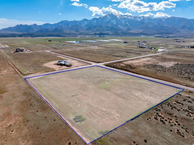 Aerial view of sparsely populated area with property parcel outlined and a mountainous background