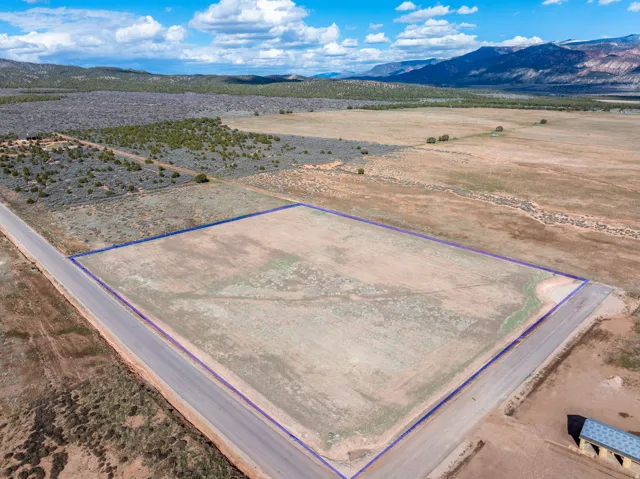 Aerial view of sparsely populated area featuring a mountainous background and property boundaries highlighted