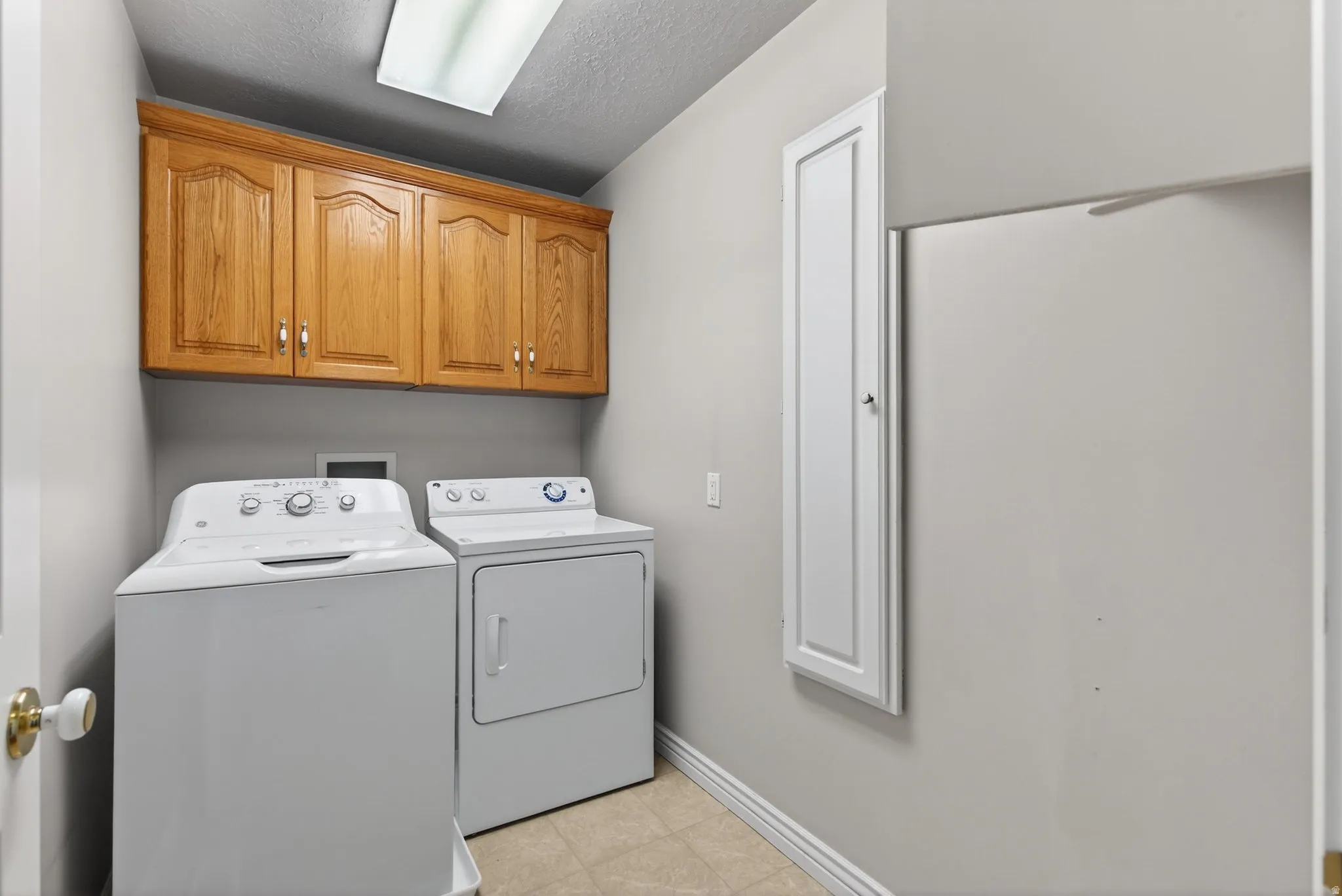Laundry room featuring washer and clothes dryer, a textured ceiling, and cabinet space