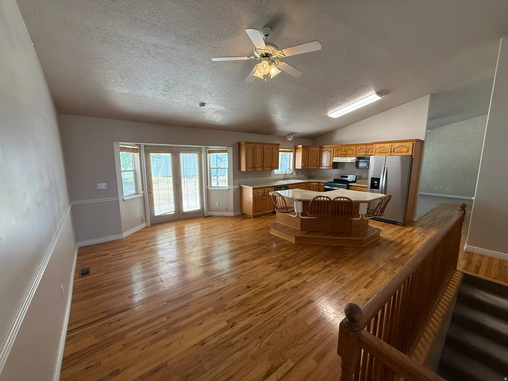 Furniture removed in Open-concept kitchen and living area featuring wood-finish flooring, vaulted ceilings, and a ceiling fan