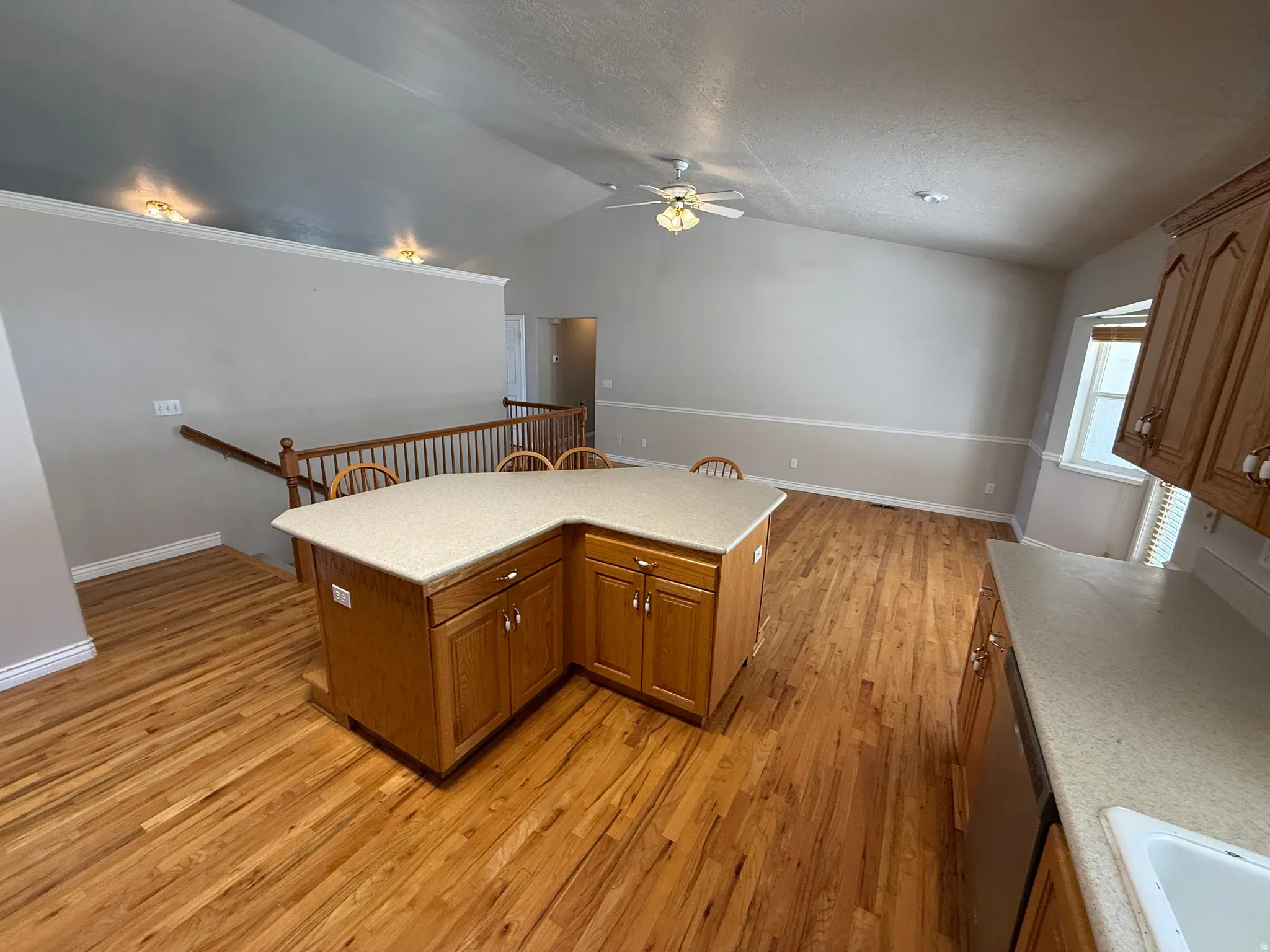 Furniture removed from Open-concept kitchen and living area featuring wood-finish flooring, vaulted ceilings, and a ceiling fan